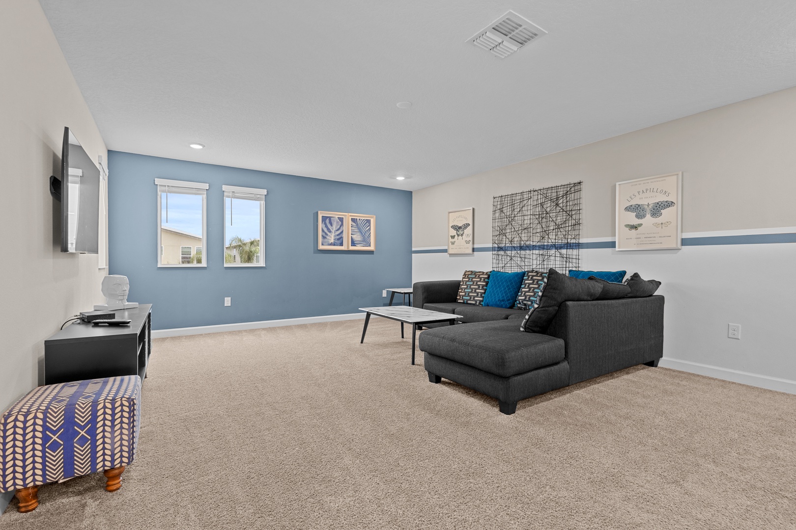 Sink into the plush sectional sofa and unwind in your spacious living room, featuring soothing blue accents and modern comfort.