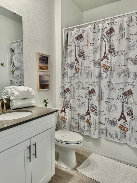 Freshen up in your stylish bathroom featuring elegant white vanity, modern fixtures, and charming Parisian-themed shower curtain.