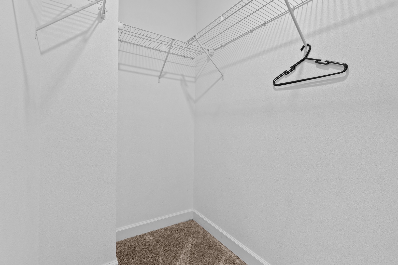 Your spacious walk-in closet offers ample hanging space with wire shelving and a hanging rod to keep your wardrobe organized during your stay.