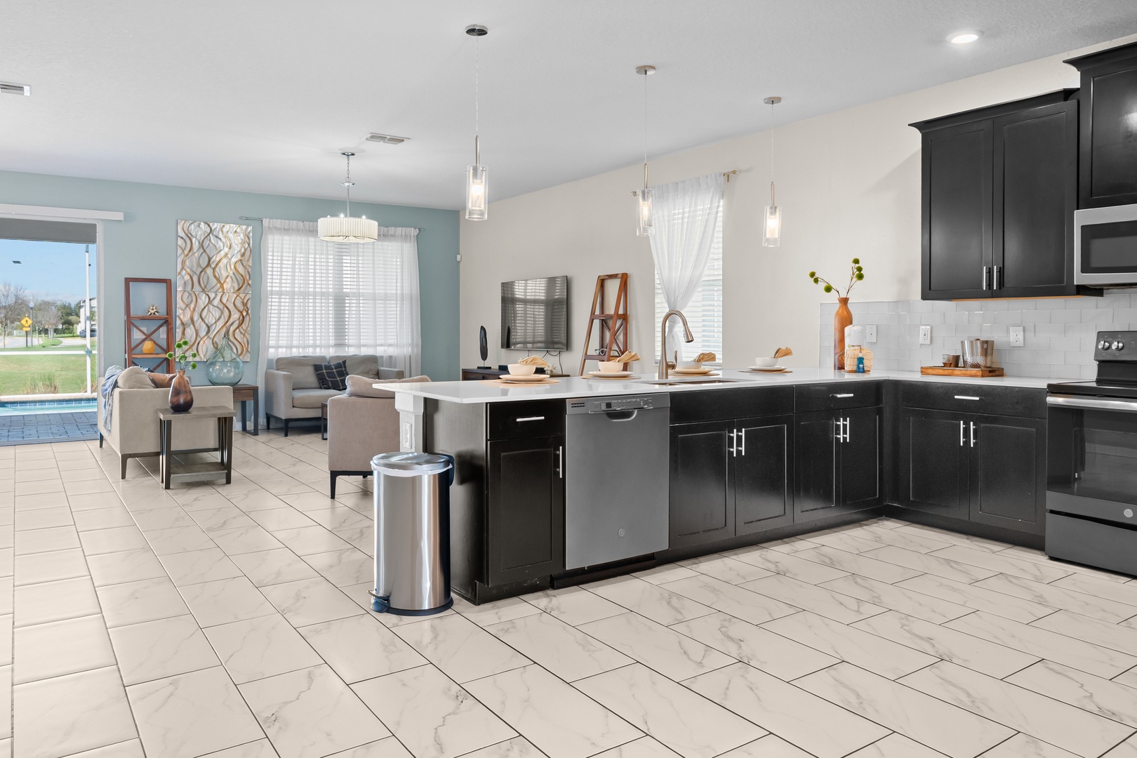 Your modern kitchen flows seamlessly into the living area, perfect for cooking and socializing with sleek black cabinets and stainless appliances.