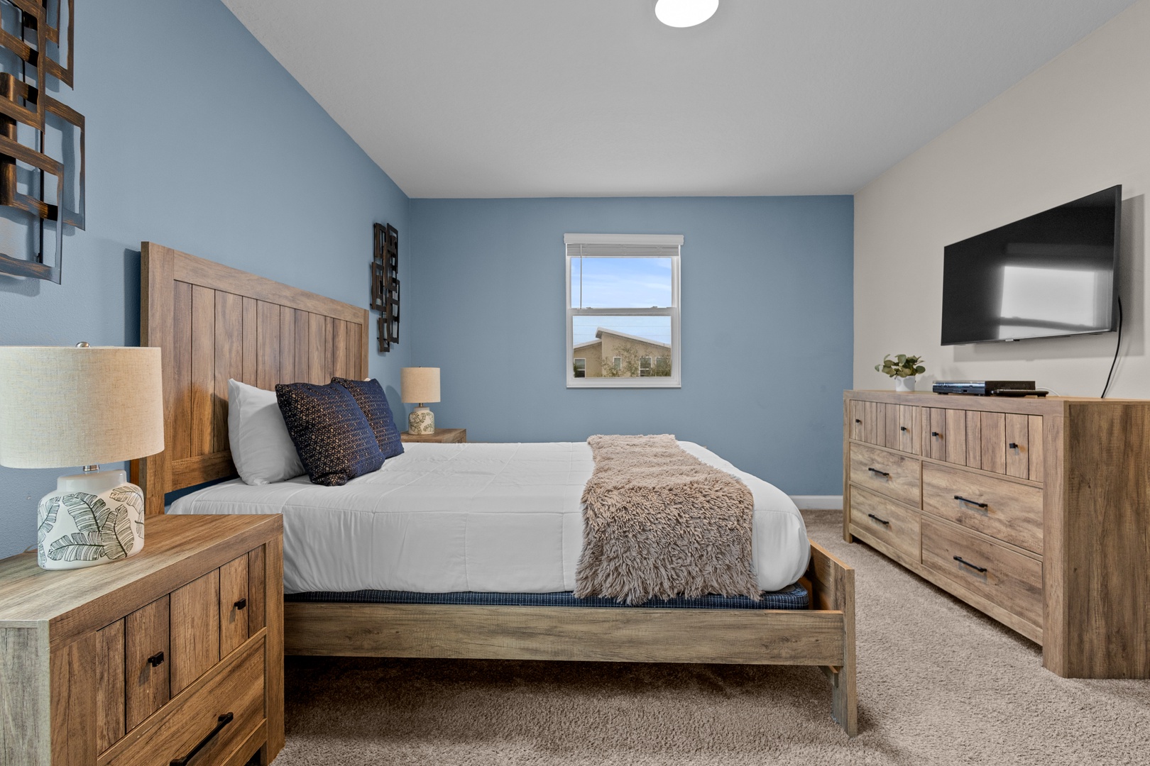 Drift off to sleep in this cozy bedroom featuring warm wood furnishings, soft linens, and calming blue walls that create your perfect retreat.