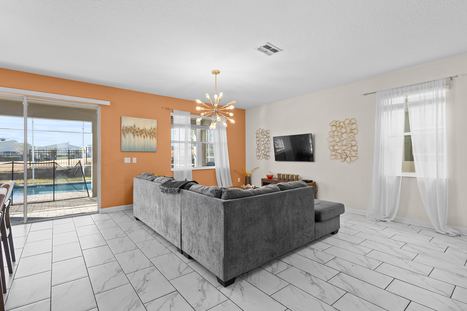 Sink into plush seating in your bright living room, where warm orange accents and modern décor create the perfect backdrop for relaxation.