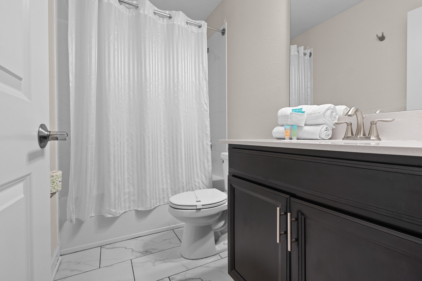 Step into your private sanctuary with a spacious tub-shower combo, elegant marble-look floors, and fresh towels waiting for your arrival.