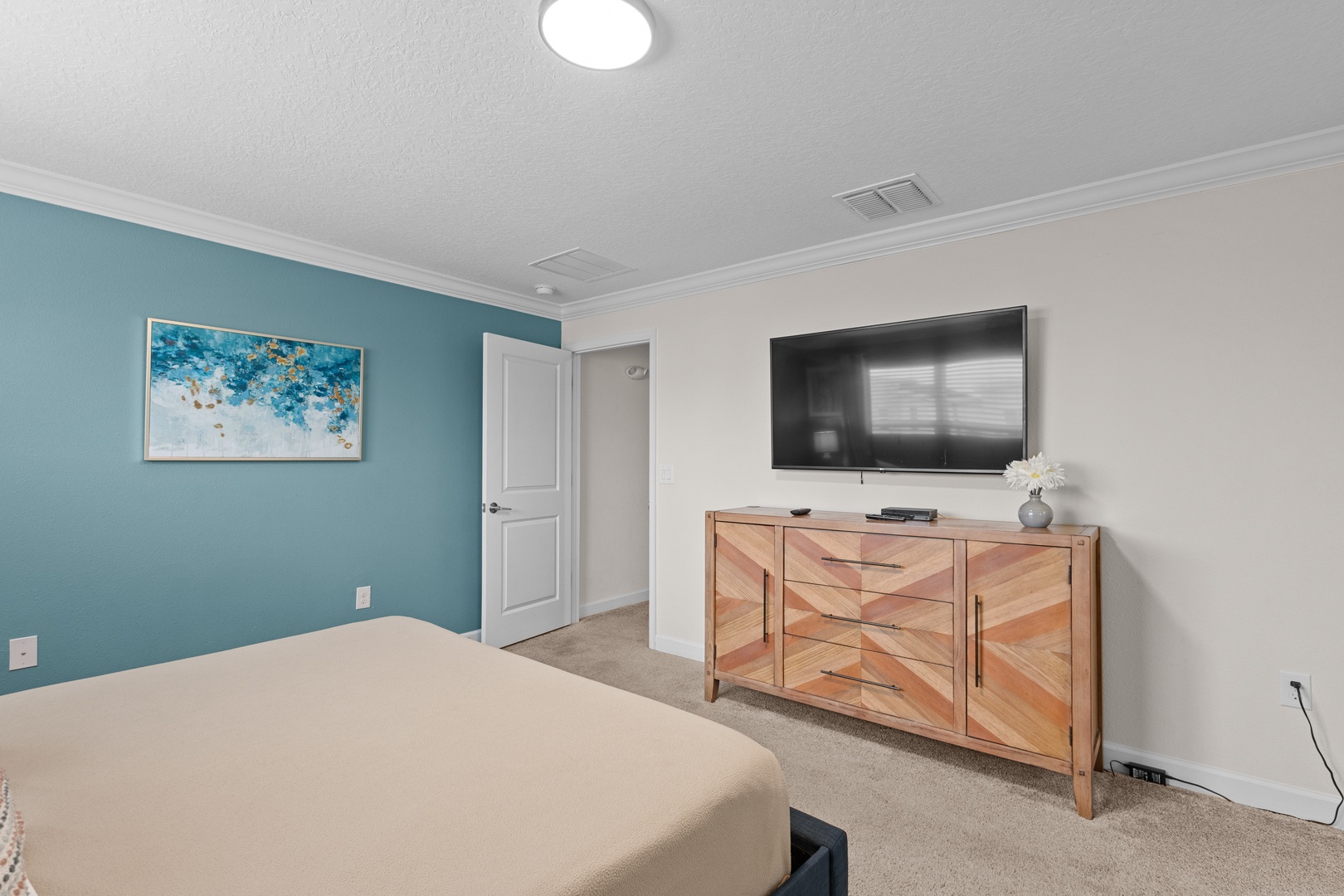 Unwind in your peaceful bedroom featuring a wall-mounted TV and stylish coastal artwork that sets a serene tone for restful nights.