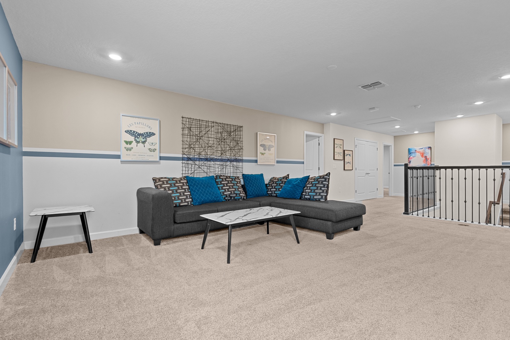 Relax in your spacious living room featuring a cozy sectional sofa with vibrant blue accents and modern coffee table.