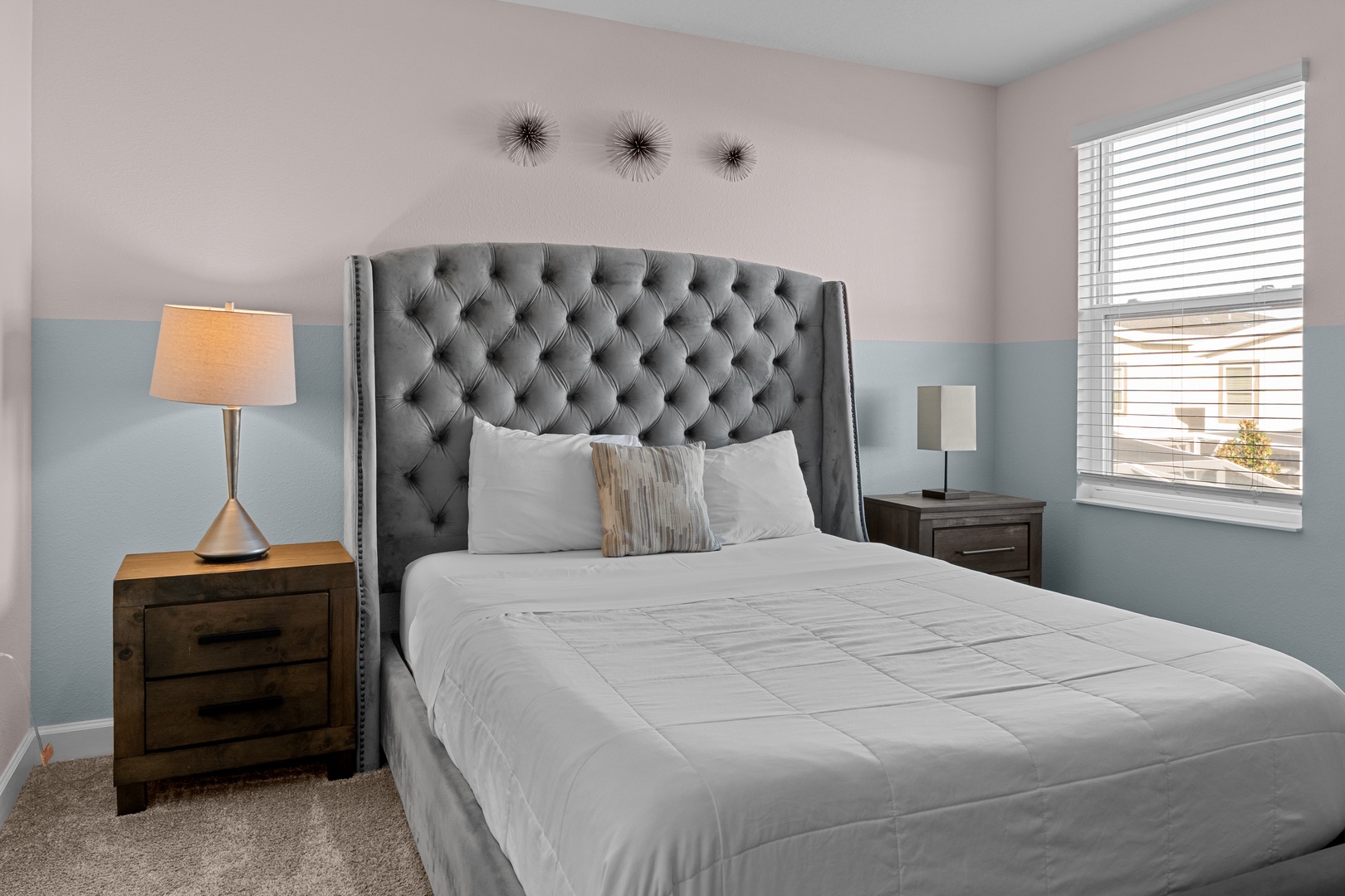 Drift off in this stylish bedroom featuring a plush tufted headboard, soft linens, and calming blue accent walls for your perfect night's rest.