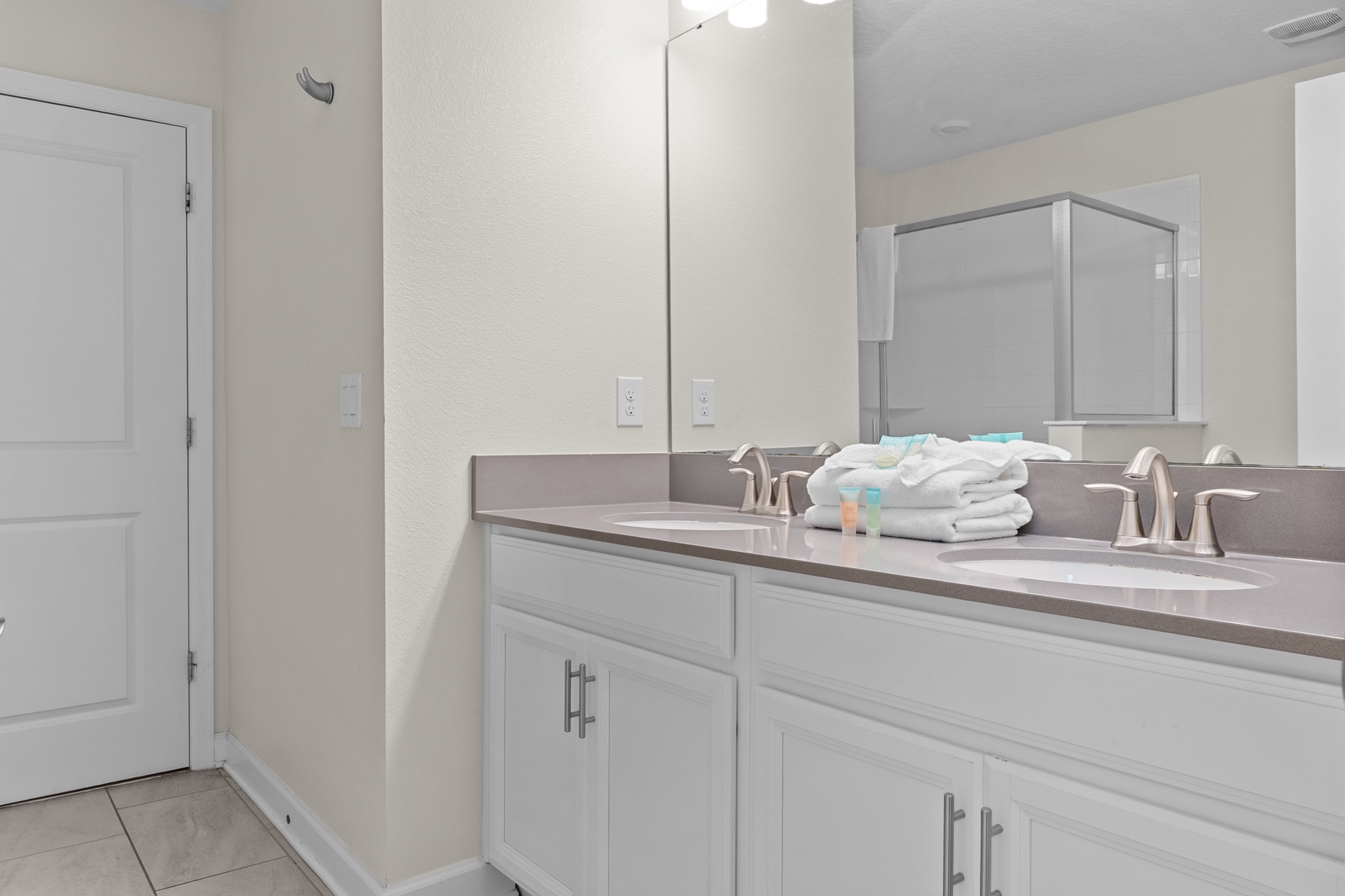 Your spacious bathroom features dual sinks with elegant countertops and fresh towels, perfect for getting ready together.