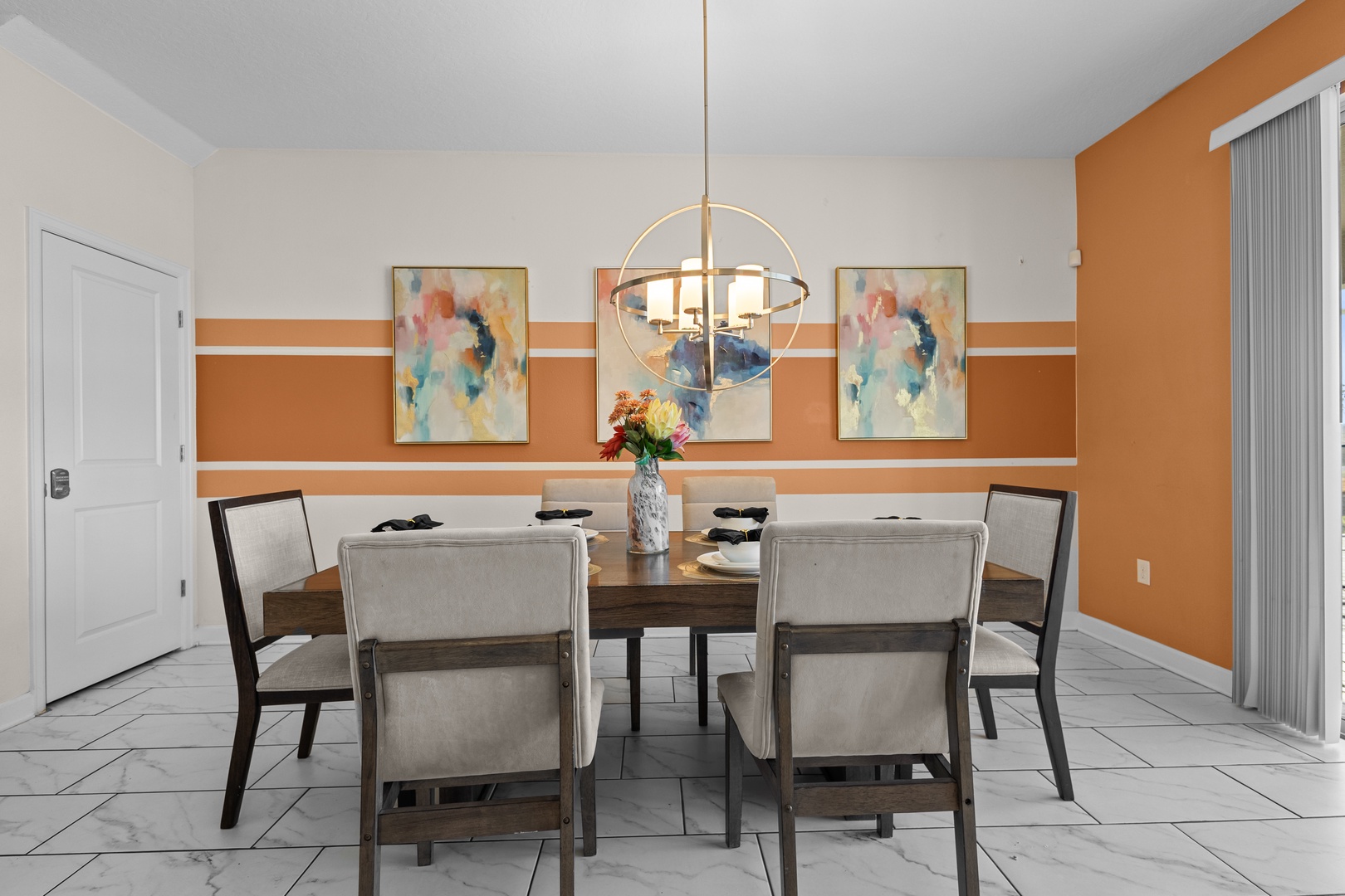 Gather around your stylish dining table where warm orange walls and elegant artwork create the perfect backdrop for memorable meals together.