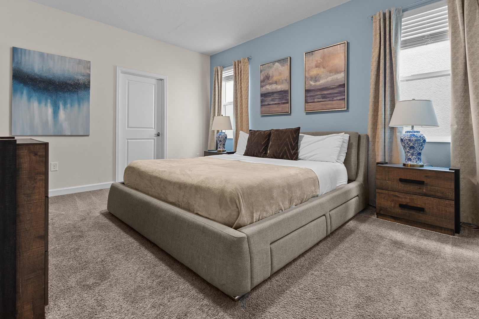 Sink into this plush upholstered bed surrounded by calming coastal artwork and warm wood furnishings for your perfect retreat.