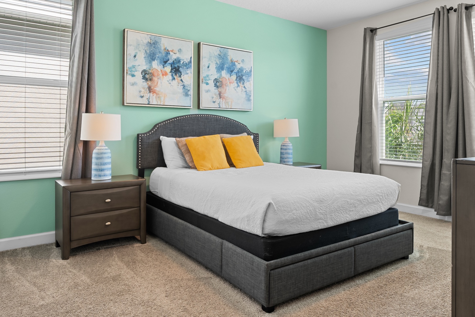 Sink into your peaceful retreat with crisp linens, vibrant artwork, and soothing mint walls that create the perfect atmosphere for restful nights.