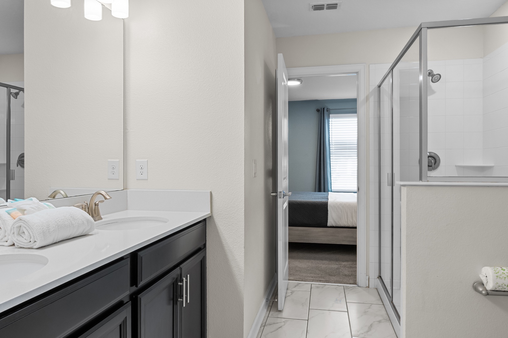 Step into your private ensuite with modern vanity, glass shower, and fluffy towels—your refreshing retreat after exploring the area.