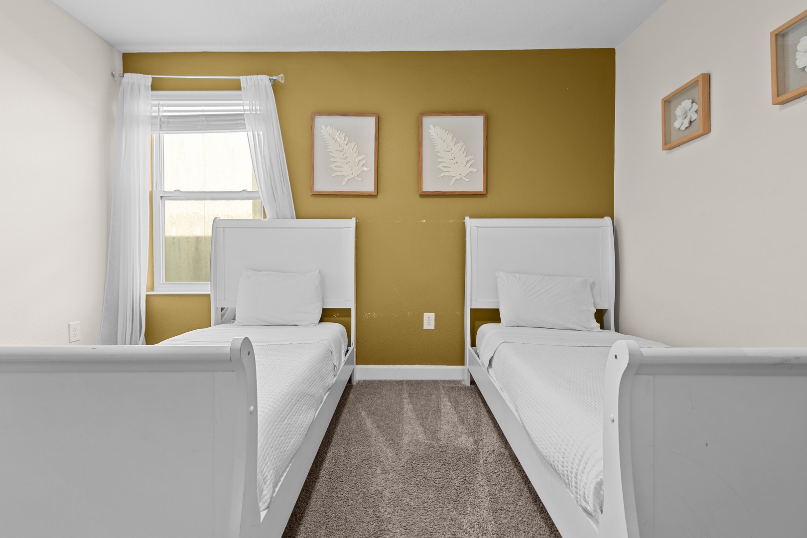 Your twin bedroom features crisp white beds with stylish mustard accent wall and natural light streaming through bright windows.
