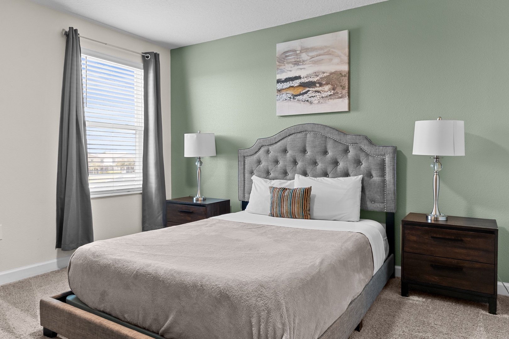 Sink into this plush tufted headboard bed surrounded by soothing sage walls and soft natural light for your perfect restful retreat.