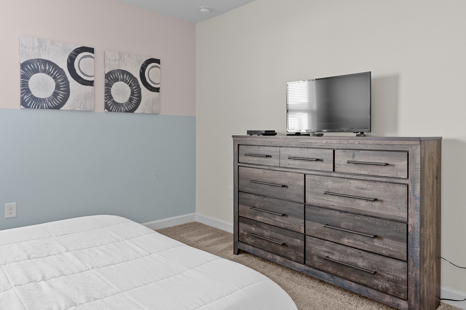 Your bedroom features a spacious dresser with ample storage and a flat-screen TV for relaxing evenings in your comfortable retreat.