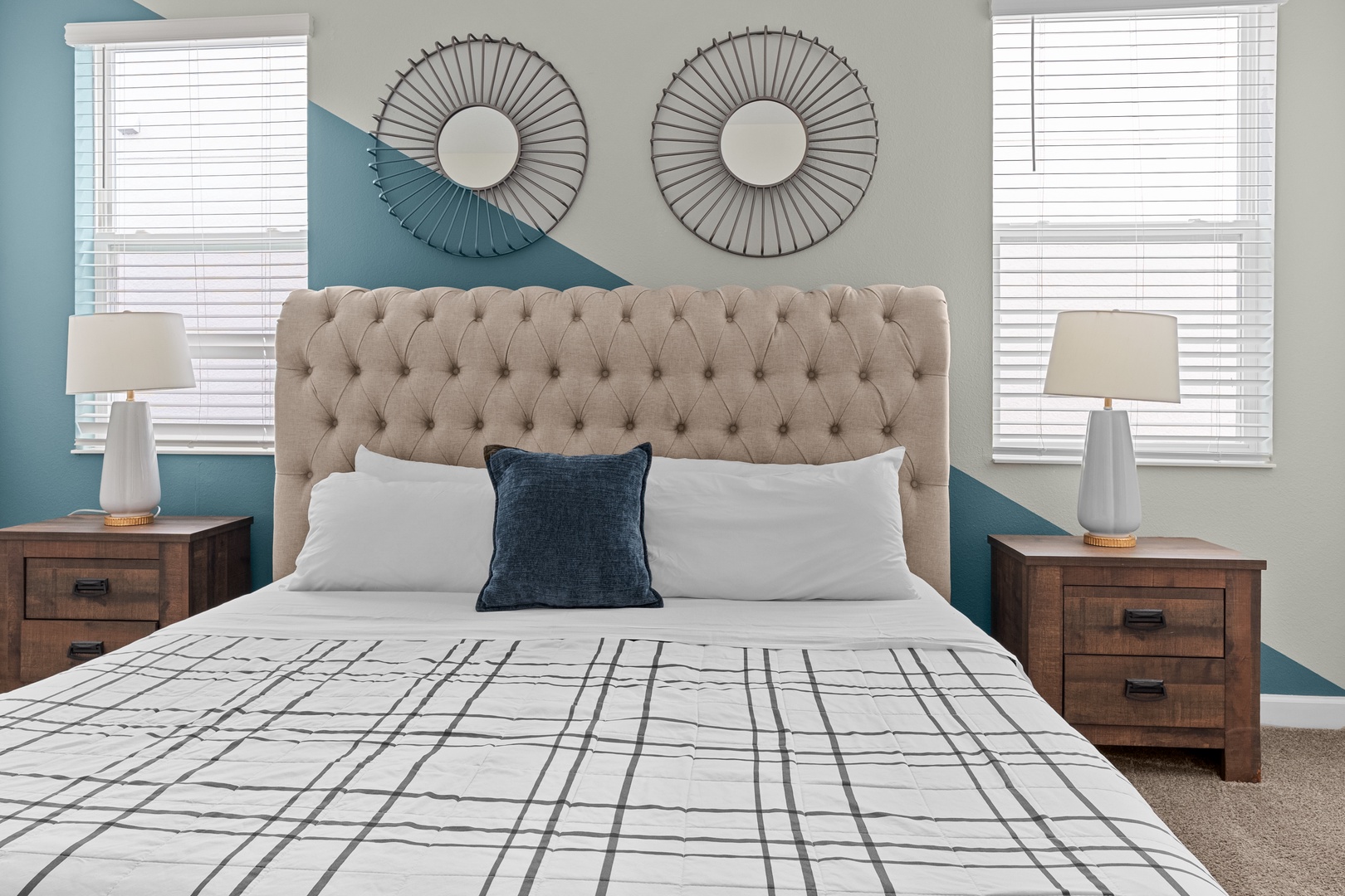 Your restful bedroom features a plush tufted headboard, soothing blue accent wall, and stylish decor that creates the perfect sanctuary for peaceful sleep.