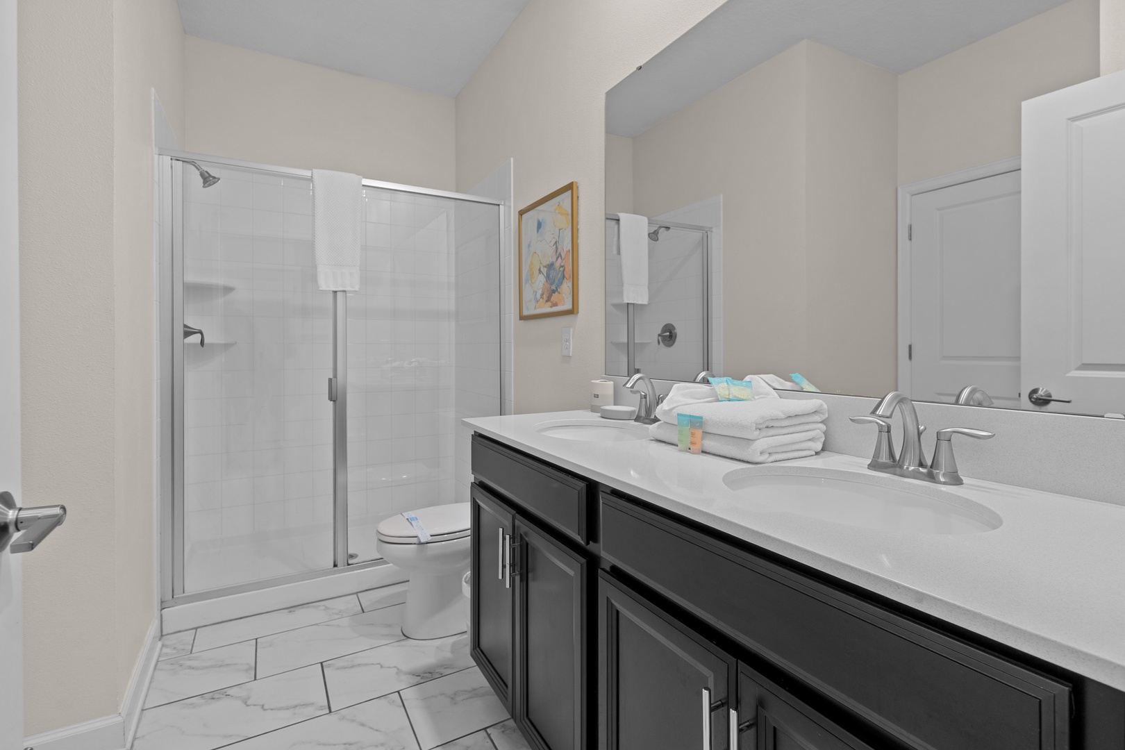 Refresh in your modern bathroom with dual sinks, gleaming counters, and a spacious glass shower—perfectly appointed for your comfort.