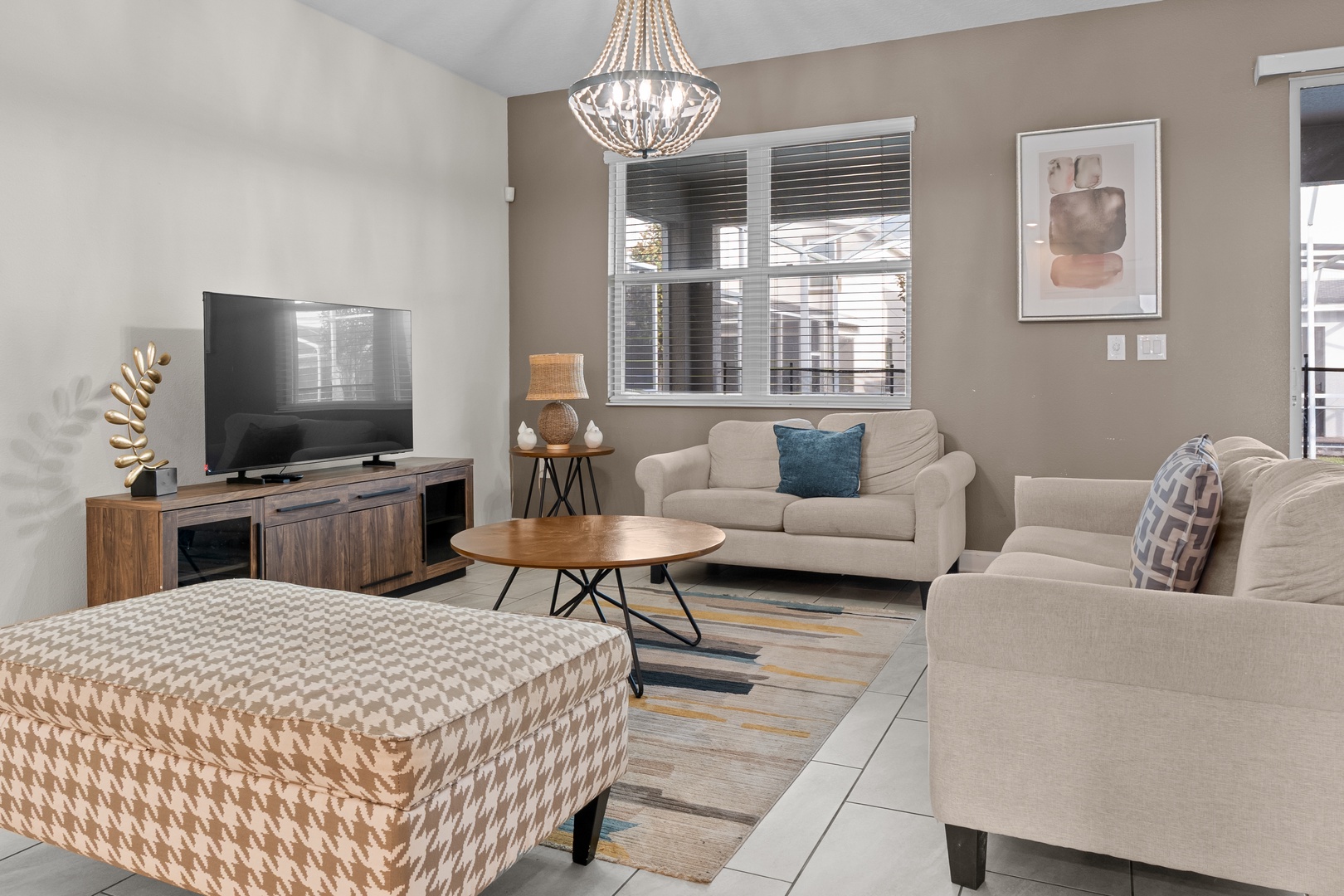 Sink into plush sofas and enjoy your favorite shows on the large TV in this beautifully appointed living room with elegant chandelier lighting.