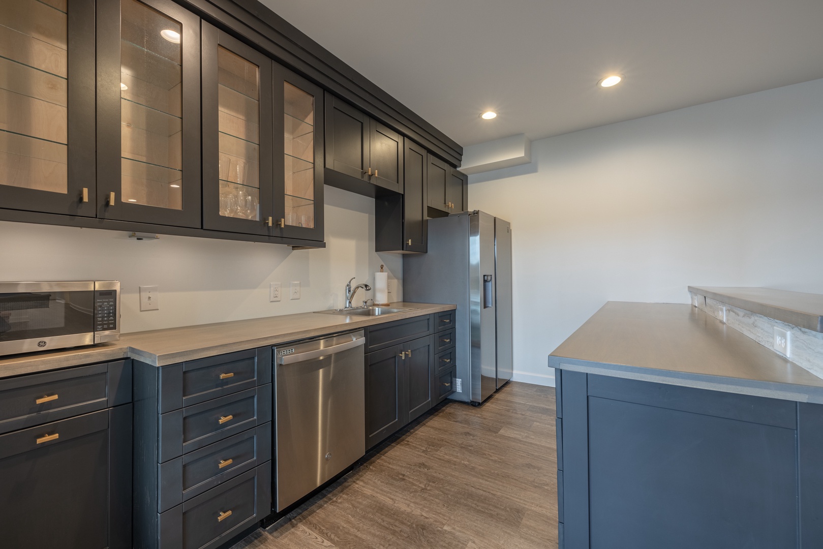 A full kitchen/bar area complete with stainless steel appliances and custom countertops in the lower makes it the ultimate hangout spot