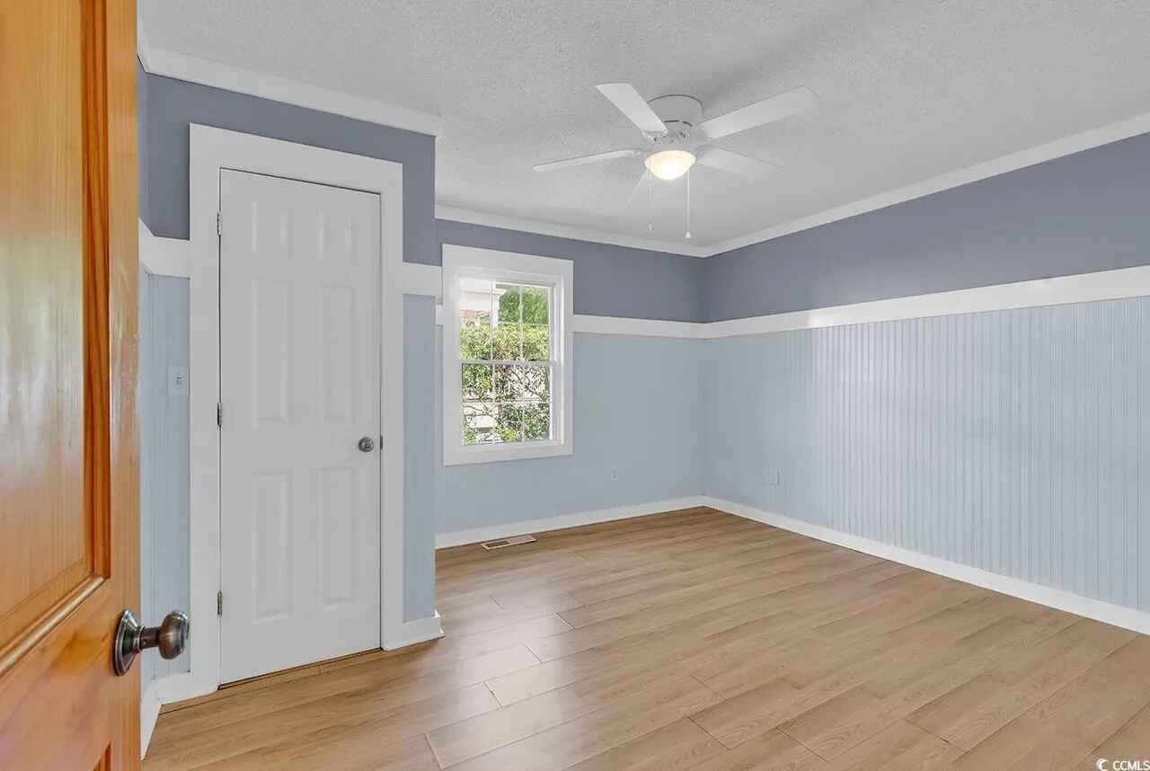 Step into your serene retreat with soft blue walls, classic wainscoting, and natural light streaming through your window.