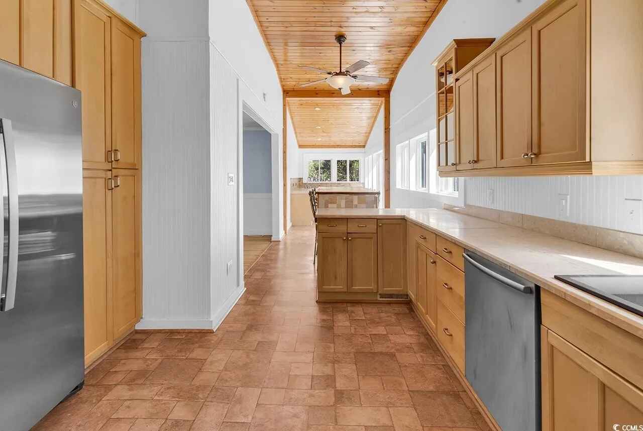 Your fully-equipped kitchen features warm wood cabinets, stainless steel appliances, and rustic ceiling beams that create a cozy cooking space.