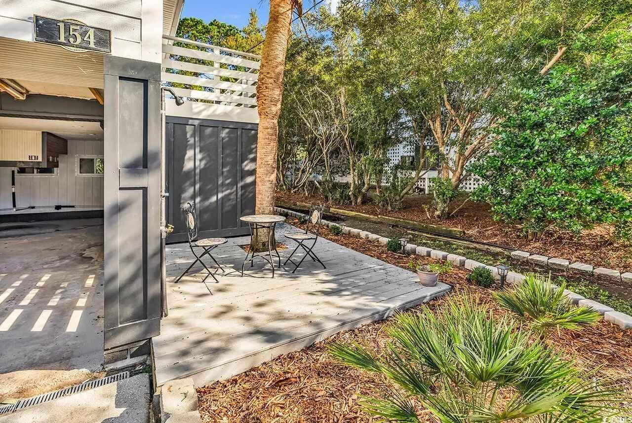 Modern property entrance with landscaped gardens and outdoor seating area at unit 154.