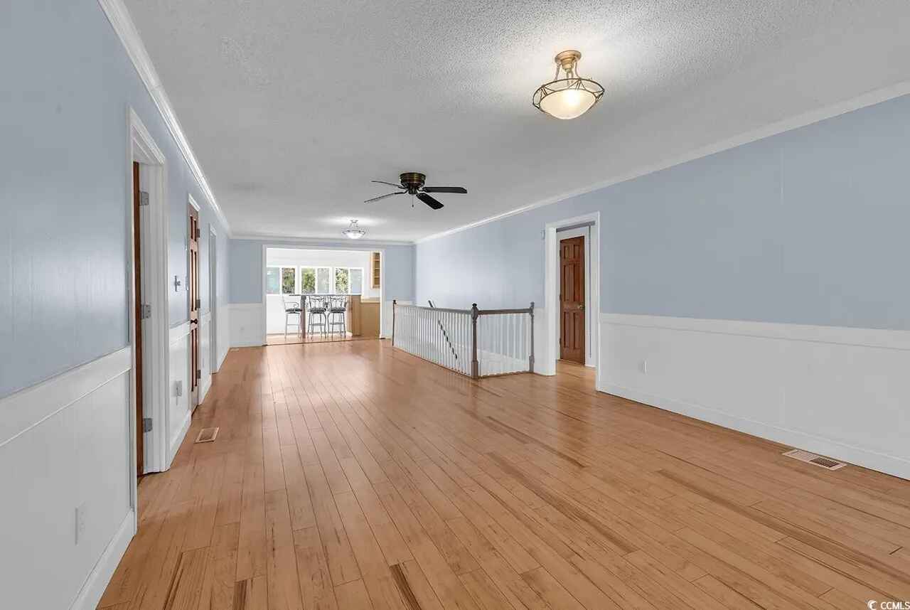 Step into your spacious upstairs retreat with gleaming hardwood floors and elegant two-tone walls creating the perfect gathering space.