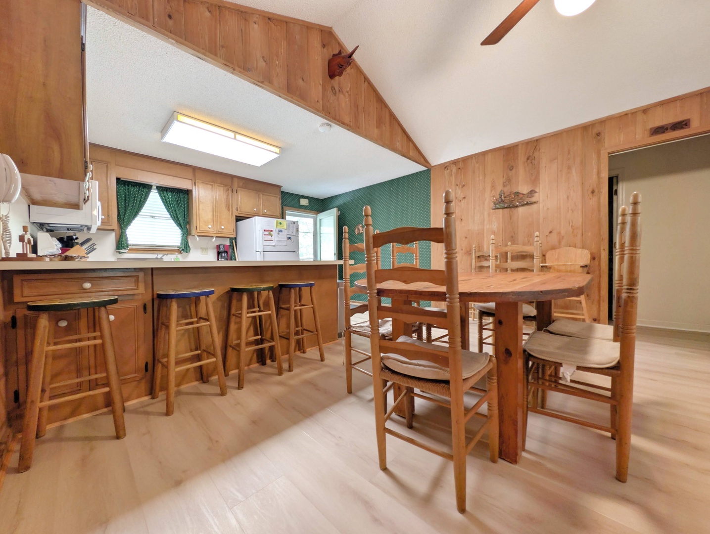 This cozy dining area features handcrafted wooden furniture, a breakfast bar with stools, and warm wood-paneled walls—your perfect spot for family meals and morning coffee.