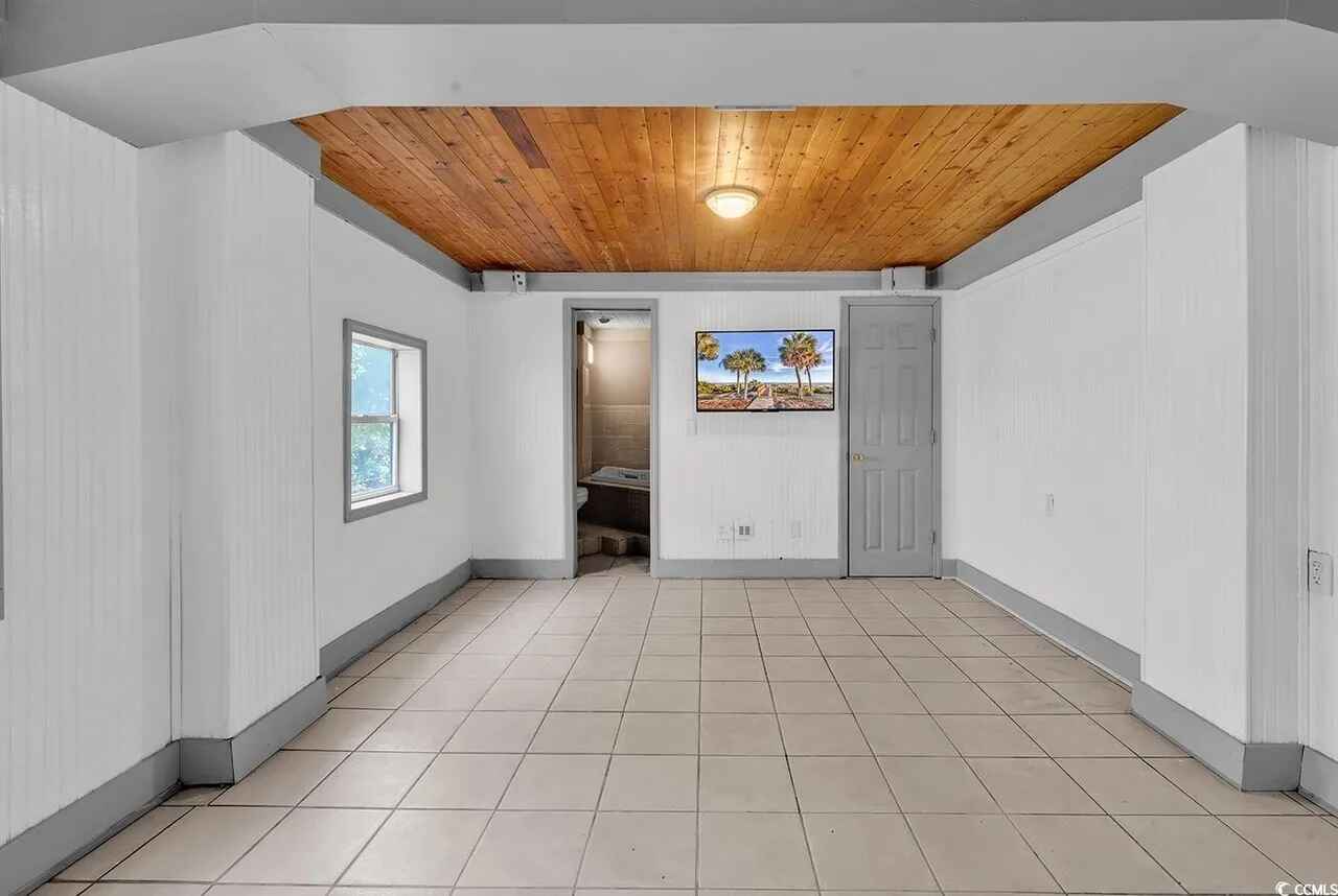 Your spacious room features striking wood beam ceilings and clean tile floors, creating a welcoming retreat with modern comfort and rustic charm.