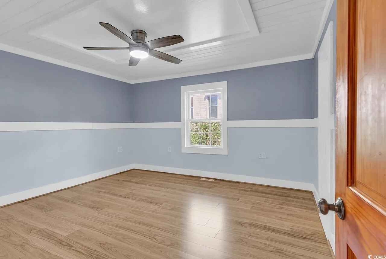 Step into your peaceful bedroom featuring soothing blue walls, gleaming hardwood floors, and a ceiling fan to keep you comfortable during warm nights.
