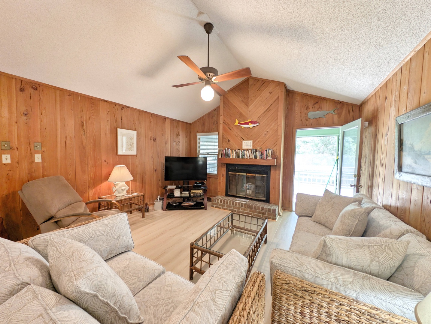 Unwind in your cozy living room with vaulted ceilings, warm wood paneling, and a crackling fireplace—your perfect retreat after exploring nearby adventures.