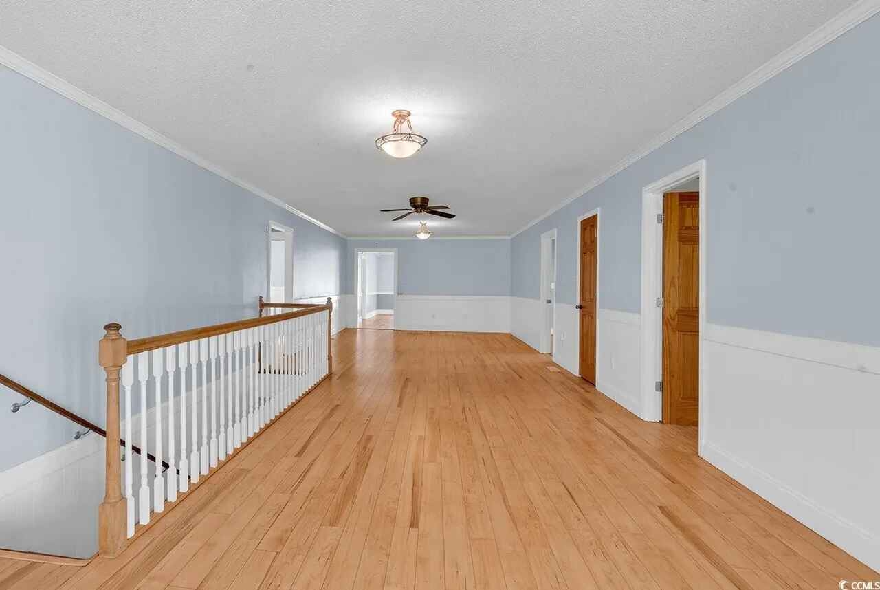 Your spacious upstairs hallway features gleaming hardwood floors and soft blue walls that create a peaceful retreat for your stay.