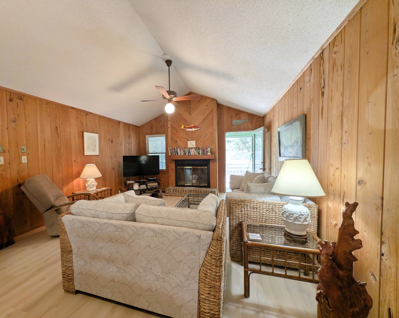 Unwind in your cozy living room with vaulted ceilings, warm wood paneling, and plush seating. The fireplace adds rustic charm while natural light flows through windows, creating the perfect space for your relaxation.