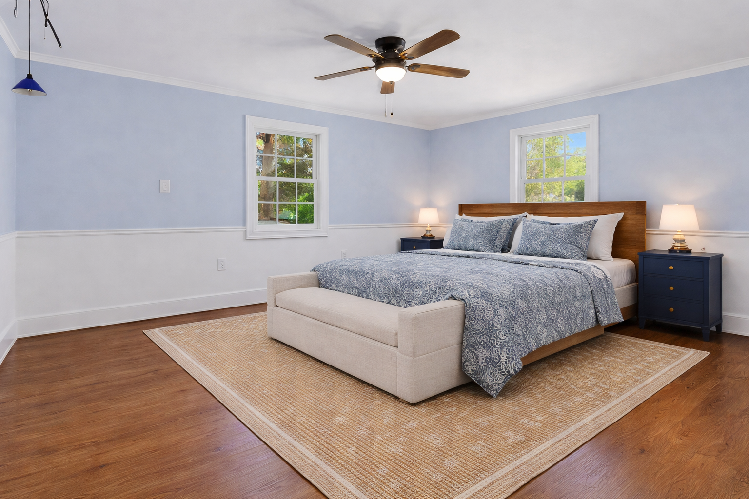 Your serene bedroom sanctuary features soft blue walls and natural light streaming through windows for peaceful rest.