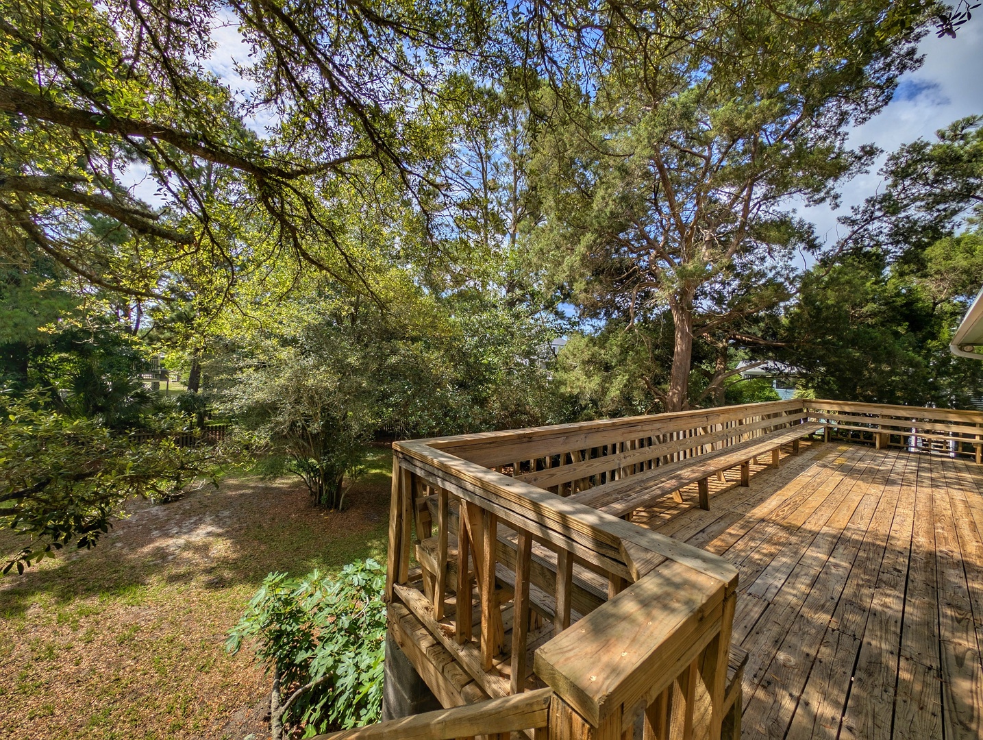 A spacious wooden deck surrounded by towering trees and lush greenery offers a peaceful outdoor retreat where you can unwind, breathe fresh air, and soak in nature's tranquility.