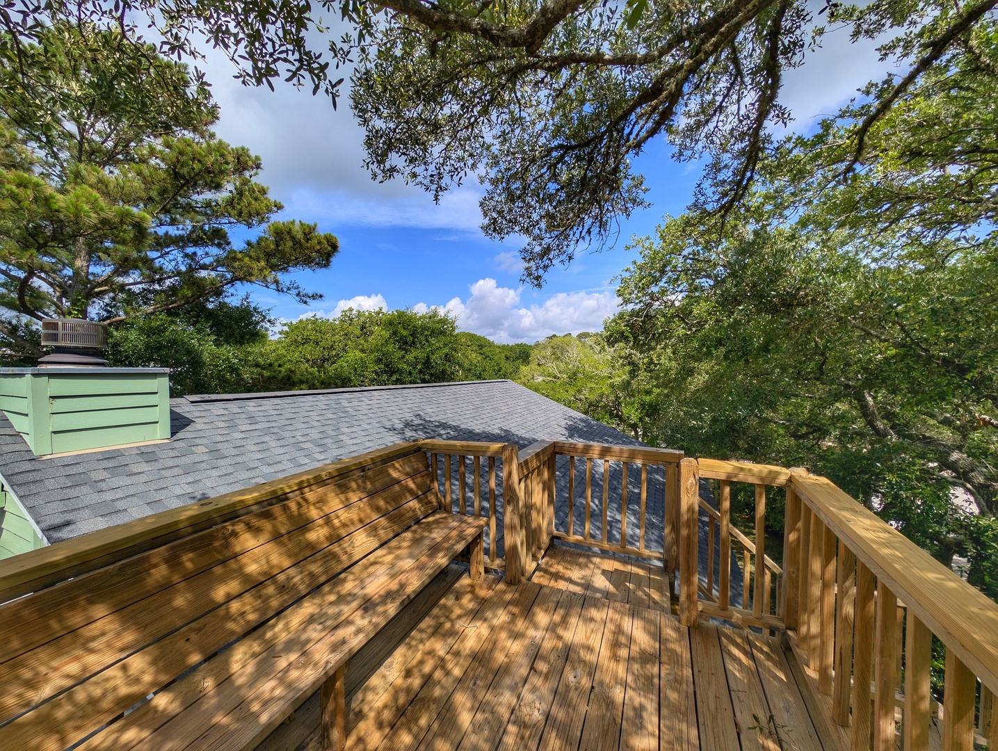 A sun-dappled deck nestled among mature trees offers a peaceful outdoor space to unwind, with built-in seating perfect for your morning coffee or evening relaxation beneath the canopy.
