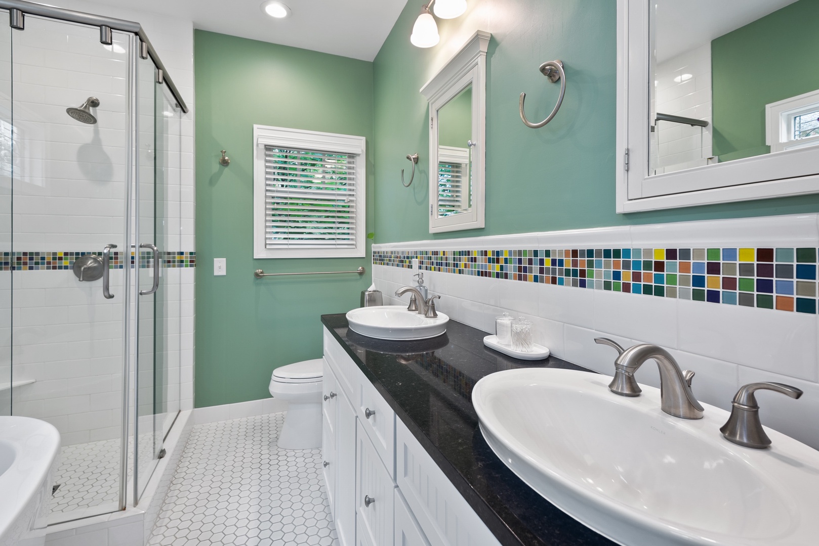 The main en-suite bath is fully remodeled with heated floors, dual-sink vanity, statement tub, & glass-and-tile shower.