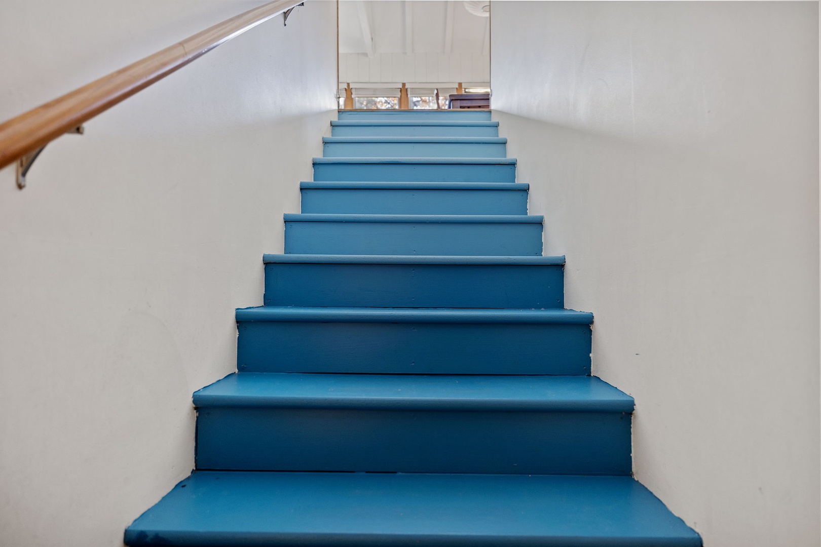 Down this flight of pretty blue stairs, you come into an inviting family room area.