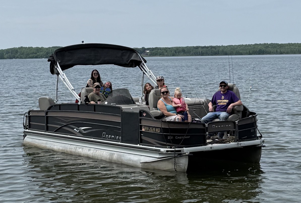 Pontoon boat on the lake near the property, surrounded by wooded shoreline—a glimpse of recreational activities available in the area.