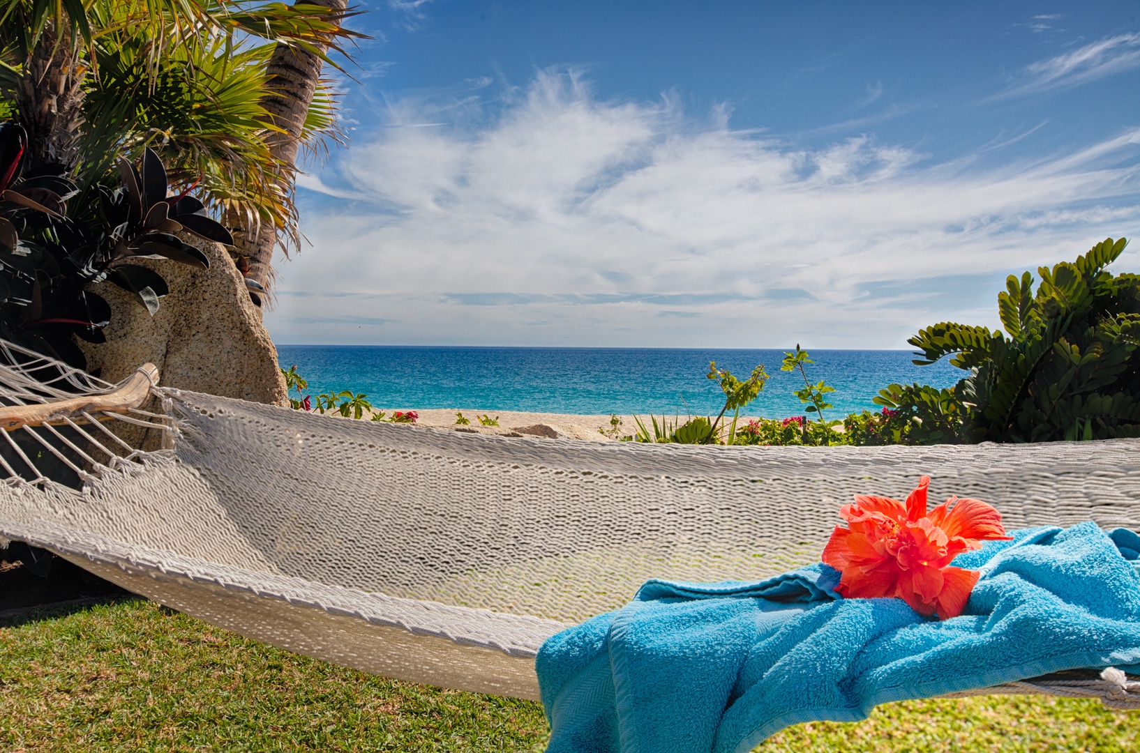 Drift away in your private hammock with turquoise towels and tropical blooms, as the pristine beach beckons just steps away.