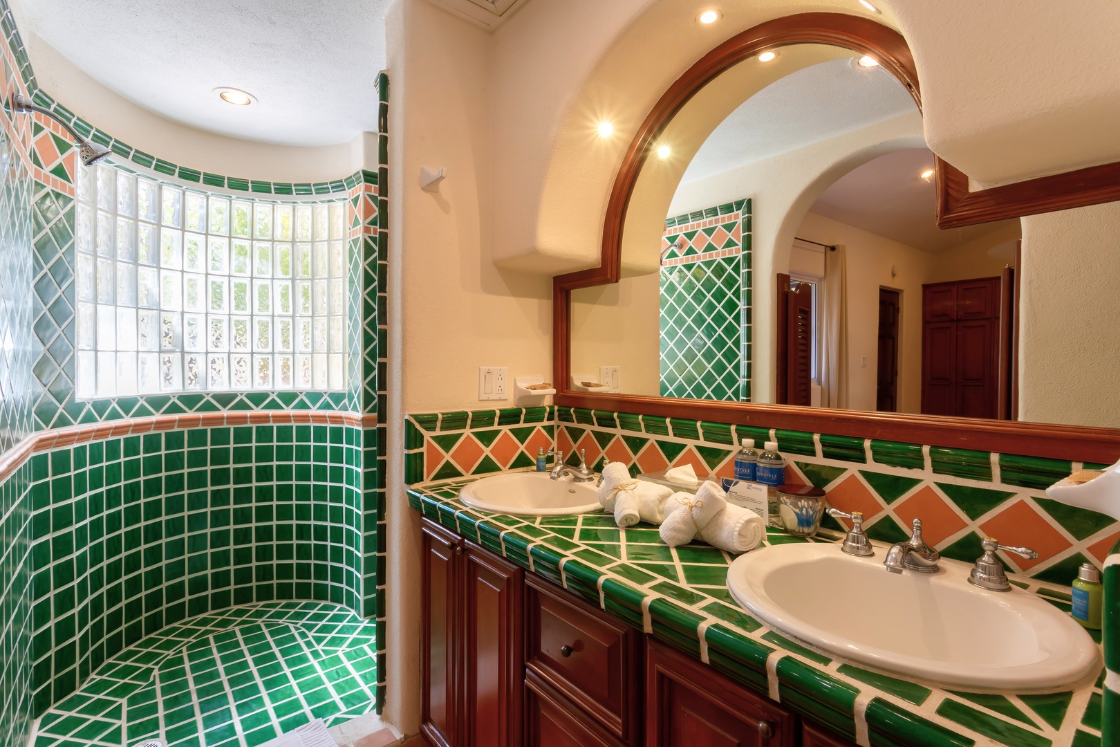 Unwind in your vibrant mosaic bathroom featuring dual sinks, elegant arched mirrors, and a luxurious tiled shower that feels like your own private spa retreat.