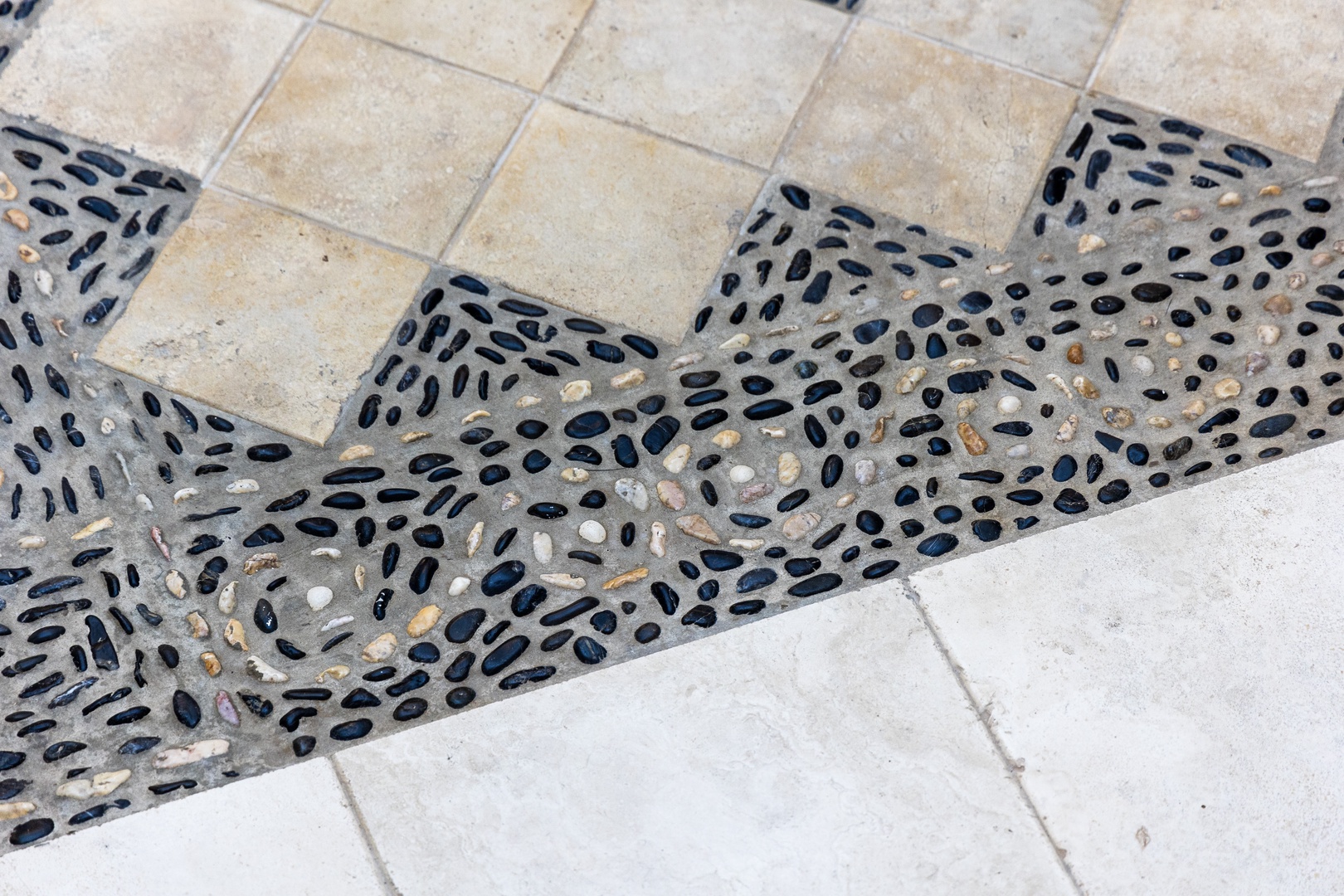 Elegant pebble and tile inlay detail graces the outdoor flooring, adding artisanal charm and coastal-inspired texture to your vacation space.