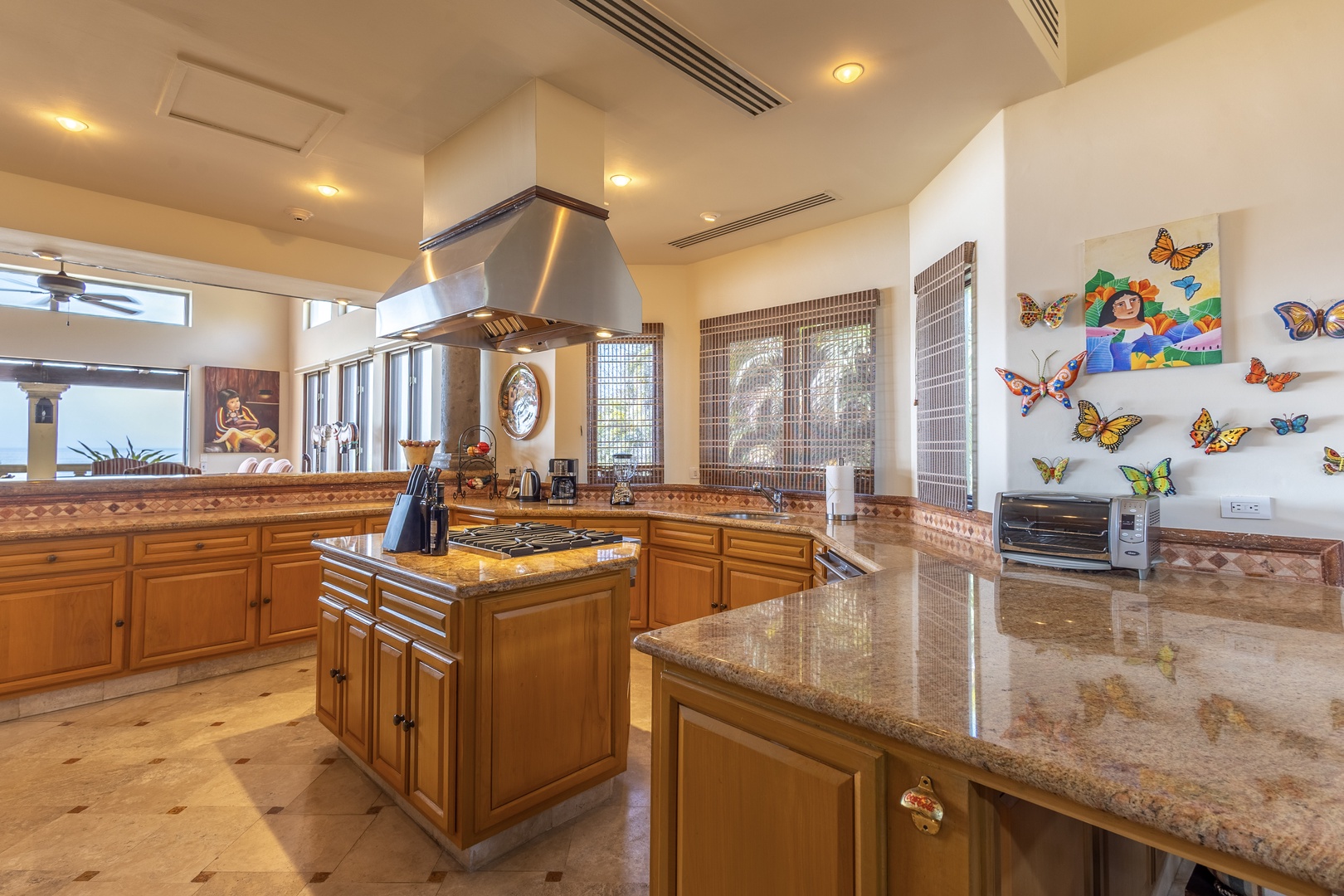 Your spacious gourmet kitchen features granite counters, a professional-grade center island with gas cooktop, stainless steel range hood, and whimsical butterfly art—perfect for preparing meals together.