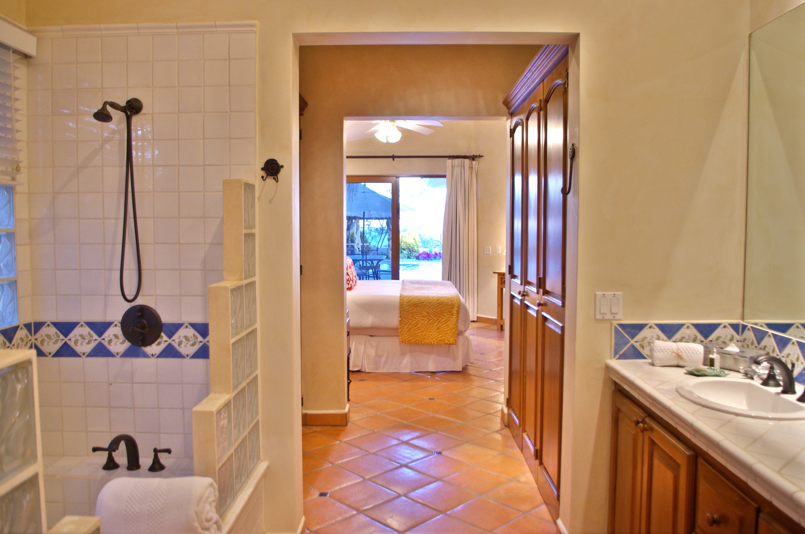 Relax in your private sanctuary with a tile-accented bathroom leading to a serene bedroom with views of the pool and patio beyond.