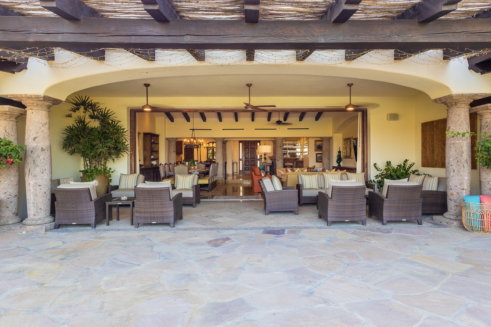 Seamlessly blending indoor and outdoor living, this covered patio offers your perfect spot to unwind with plush seating, natural stone columns, and warm rustic beams overhead.