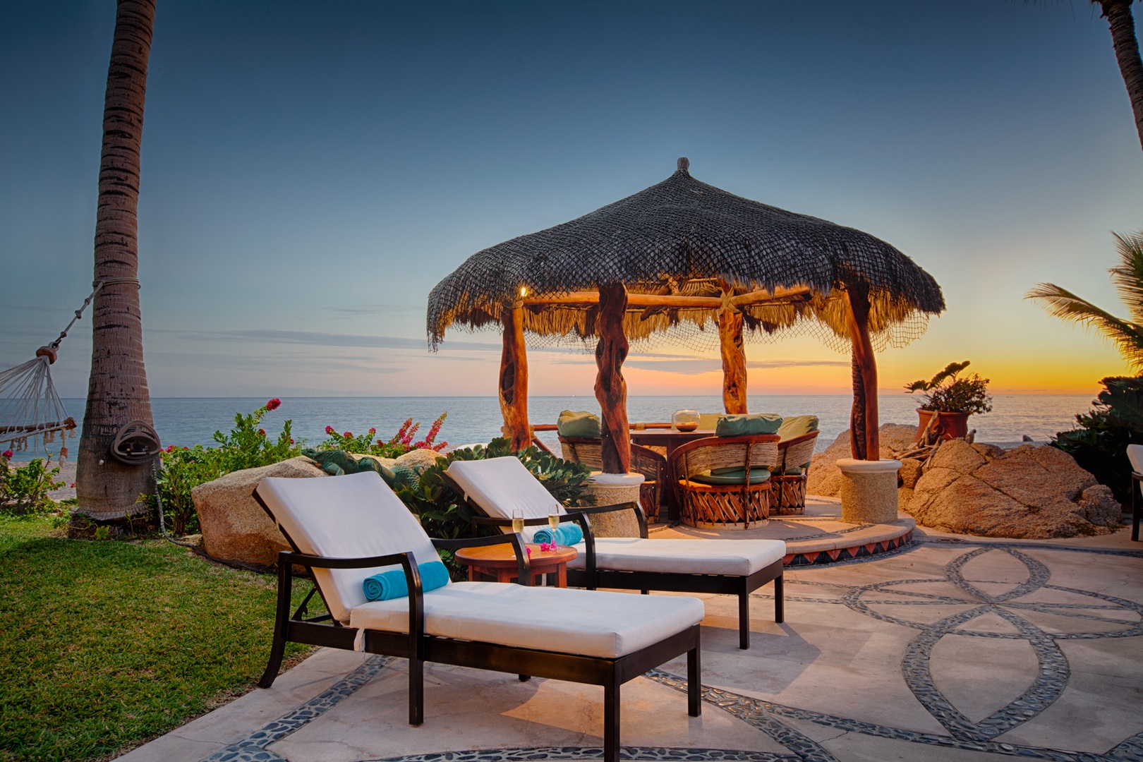 Beachfront paradise with thatched palapa, loungers, and stunning sunset views create your perfect tropical escape.