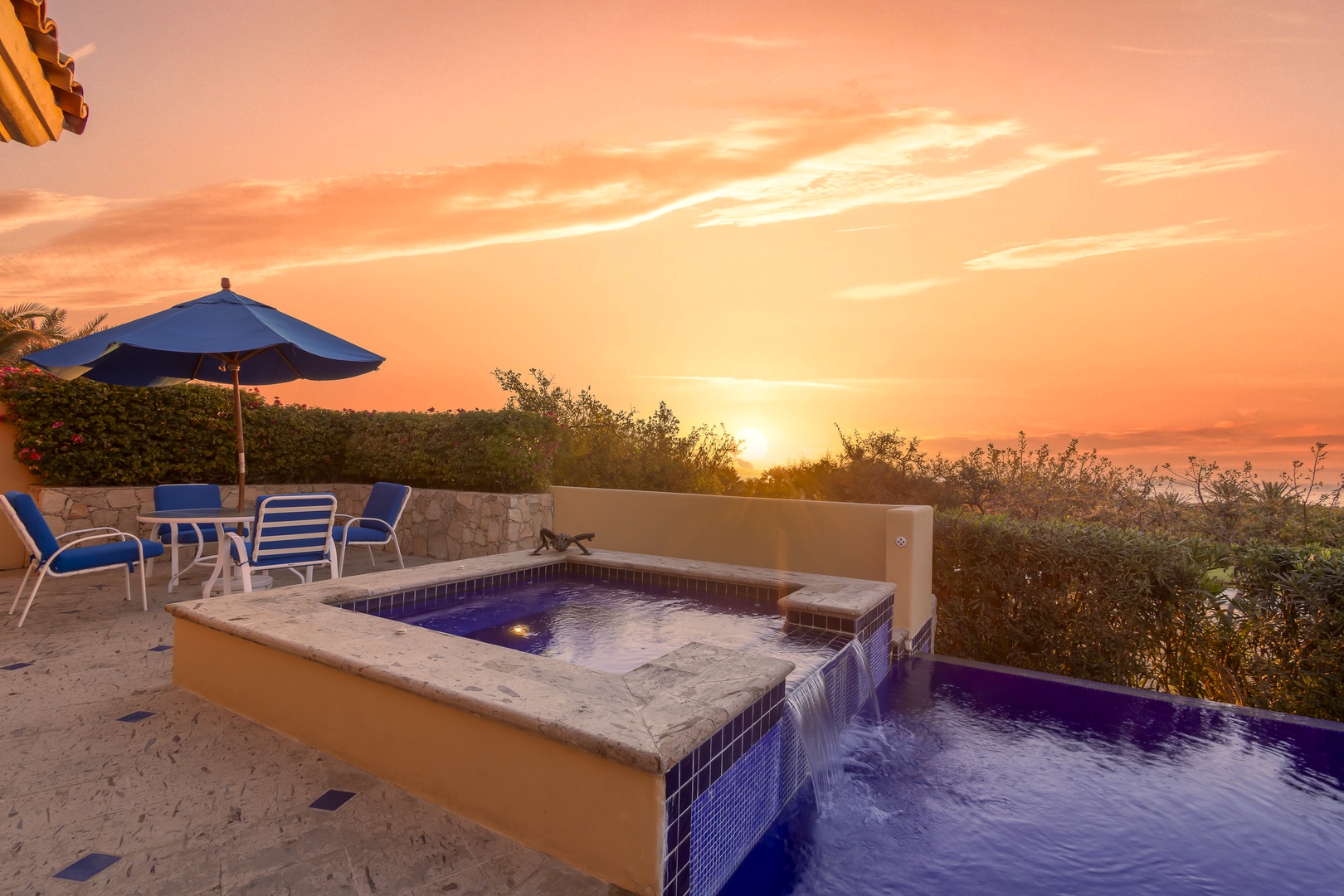 Stunning sunset views paint the sky as evening approaches this beautiful outdoor pool area with comfortable seating.