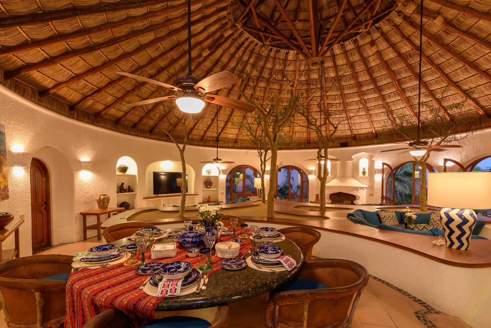 Gather around this stunning circular dining table under a traditional palapa roof, where warm evenings and memorable meals await you in this unique, artfully designed space.