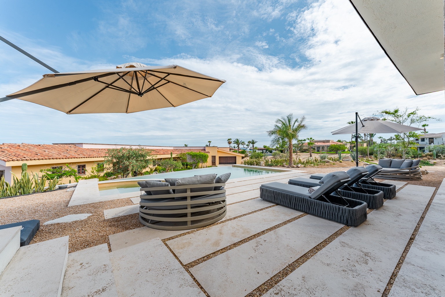 Lounge by your private pool under the shade of a patio umbrella, soaking in the tranquil surroundings and bright blue sky. Perfect for unwinding with a cool drink in hand.