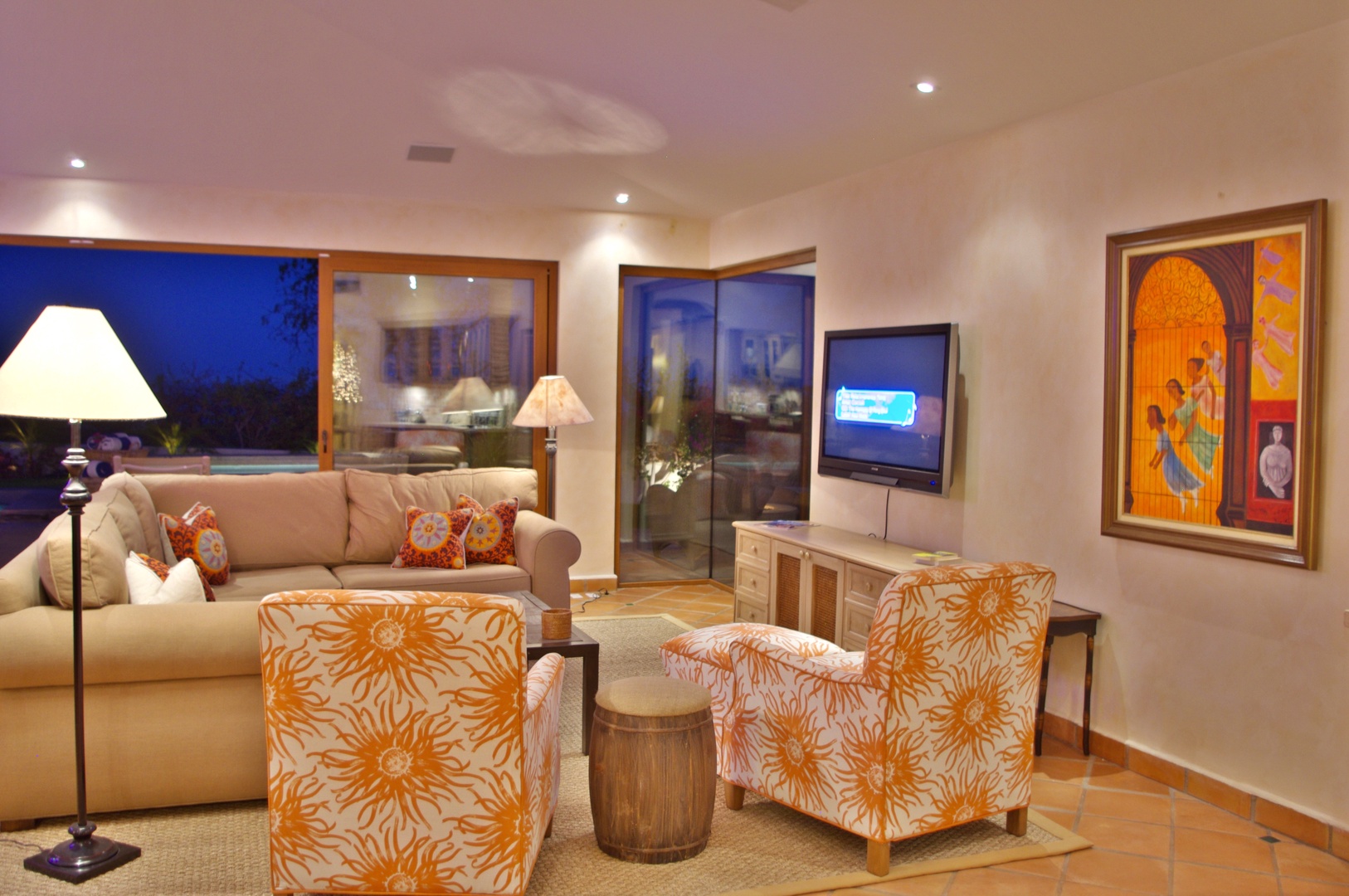 Sink into plush seating and unwind in your warmly lit living room, where artwork, ambient lighting, and evening views through expansive windows create your perfect retreat.