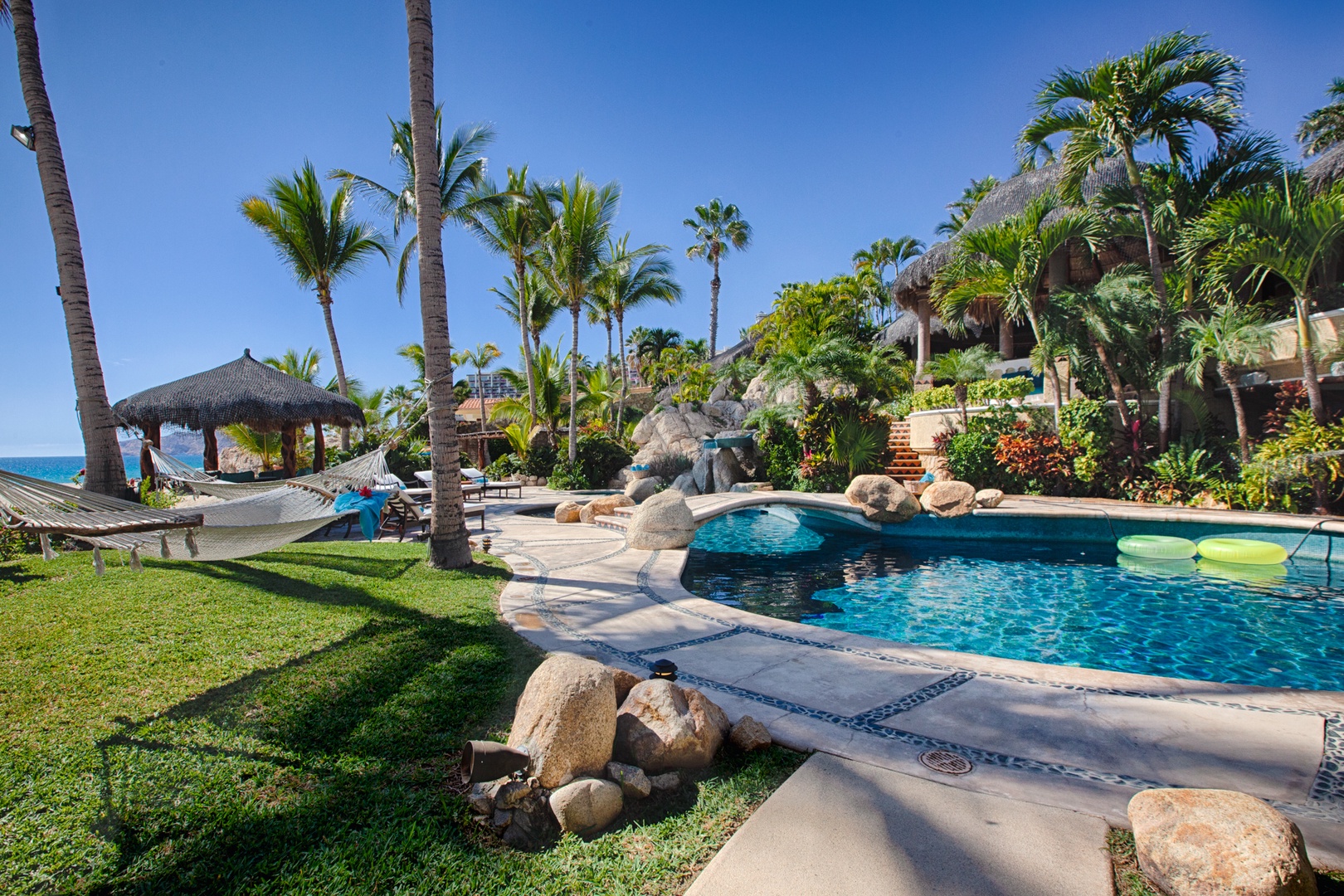 Tropical beachfront resort with swimming pool, palm trees, and ocean access creating the perfect vacation setting.